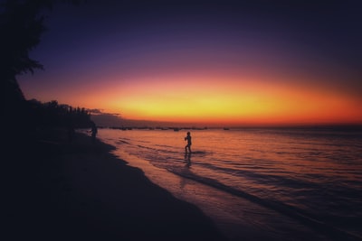 在日落轮廓的人站在岸上
